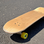 ** A classic Canadian maple skateboard deck, slightly worn with use, leaning against a textured asphalt surface. Focus on the wood grain and the details of the deck's shape. The background should be blurred but suggest an urban environment like a skate park in Milan (Parco Lambro or similar). Emphasize the warm, natural feel of the wood.

**